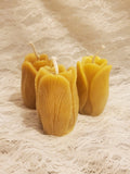 Three yellow candles on a textured beige surface