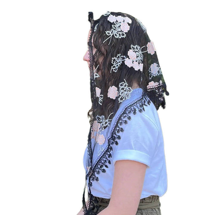 Person wearing a floral embroidered veil and light blue top on a white background