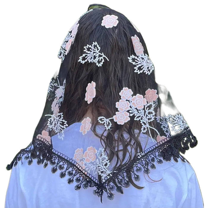 Person wearing a floral embroidered veil with a white background