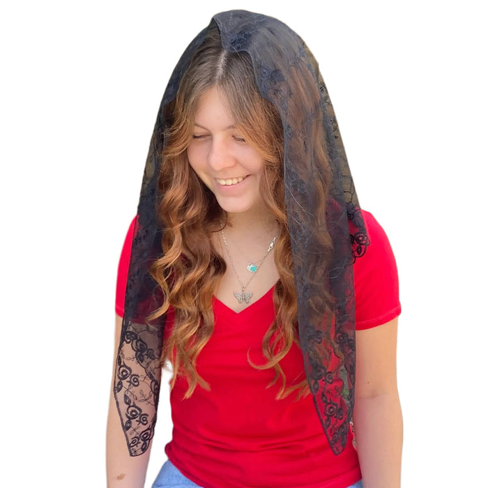 Woman wearing a red shirt with a black lace veil over her shoulders on a white background