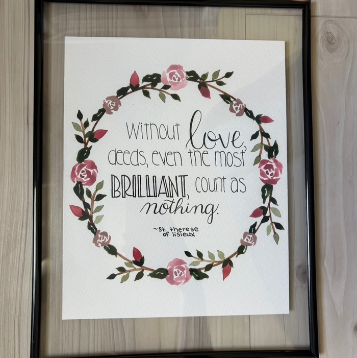 Framed print with floral design and text on a wooden surface